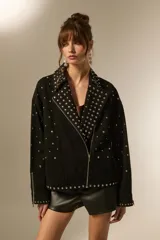 Campera de jean negra con tachas plateadas en el cuello, solapas y parte delantera. Tiene cierre asimétrico, bolsillos laterales con cierre y puños con cierre.