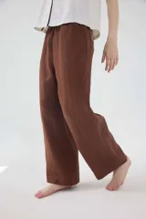 Pantalón de lino color beige, de silueta relajada, tiro medio-alto, cintura elastizada con cordón ajustable, bolsillos laterales y bolsillos traseros.