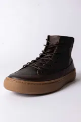 Championes de caña alta confeccionados en cuero marrón oscuro, con cordones al tono y suela de goma color caramelo.