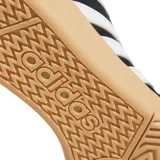 Championes Adidas Hoops 4.0 de corte bajo, con exterior de cuero sintético negro, puntera de gamuza y las icónicas tres tiras laterales en blanco. Presenta una suela tipo cupsole de goma en color caramelo y detalles en blanco en el talón.