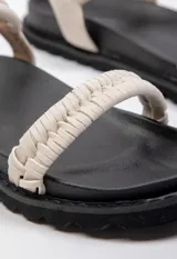 Sandalia baja negra con doble tira en el empeine tejida en beige y negro, tira de agarre en el tobillo con hebilla y plataforma de 3 cm de alto.