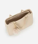 Cartera satchel mediana color beige, con cierre de cremallera, correa de mano y bretel largo desmontable. Incluye un llavero de pompón de piel sintética.