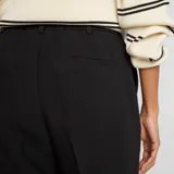 Pantalón negro de vestir, corte pitillo, con bolsillos laterales y traseros.