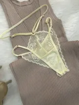 Conjunto de lencería de encaje color champagne, compuesto por un bralette estilo top con cierre frontal de gancho y breteles regulables, y una tanga de tiro alto con tiras laterales ajustables.