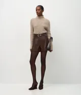 Short de poliuretano color negro, de corte recto con pinzas frontales y largo corto. Incluye un cinturón fino con hebilla y pasantes metálicos.