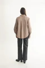 Camisa color beige de corte clásico con cuello, mangas largas y bolsillo frontal.