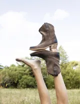 Bota corta estilo western de cuero color marrón, con taco cuadrado de 5 cm y diseño clásico. Presenta un acabado desgastado en la puntera y el talón.