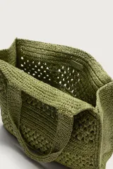 Bolso tipo shopper de color naranja con acabado trenzado y diseño estructurado. Cuenta con compartimento principal y dos asas cortas de mano.