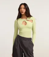 Blusa manga larga de microfibra color verde claro, con cuello redondo y diseño ajustado. Presenta un escote diferenciado tipo gota con un ribete y detalles de aberturas en el frente.