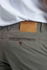 Pantalón cargo gris de gabardina, corte slim, con bolsillos laterales con solapa y bolsillos traseros con ojal y botón. Presenta efecto teñido en la tela.