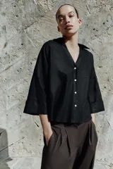 Camisa de corte holgado confeccionada en mezcla de lino, con estampado de rayas verticales en color marrón y blanco. Presenta cuello solapa, escote en pico, cierre frontal con botones y mangas amplias por debajo del codo con puños definidos.