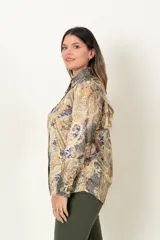 Camisa de satén con estampado paisley en tonos mostaza, azul y marrón. Tiene cuello camisero, mangas largas con puños abotonados y cierre frontal con botones dorados.