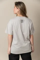 Remera gris con estampa de la letra M en negro y cadena plateada en el cuello.