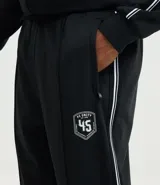 Pantalón deportivo color bordó con rayas blancas laterales, cintura elástica con cordón ajustable, bolsillos laterales y logo pequeño en el muslo.