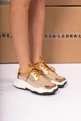 Championes urbanos color beige con detalles en blanco y marrón. Presentan cordones marrones, puntera y talón con textura símil reptil, y suela chunky blanca con base negra.