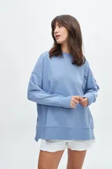 Buzo celeste de corte holgado con cuello redondo y mangas largas. Estampado en la espalda con la frase "Chasing sunbeams through fields of flowers".