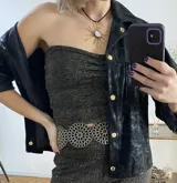 Camisa negra de cuero sintético con botones dorados.