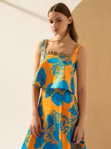 Top con estampado de cerezas en tonos naranja y azul, con breteles finos y detalle de volados en el escote.