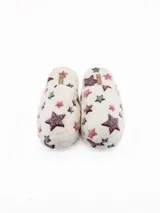 Pantuflas de peluche color crema con estampado de estrellas en tonos bordó y gris oscuro.