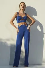 Conjunto de dos piezas color azul eléctrico, compuesto por un top corto con escote corazón y detalle de argolla central, y un pantalón de tiro alto con aberturas laterales en la cintura decoradas con argollas metálicas.