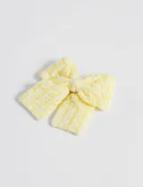 Broche para el pelo en forma de lazo, color amarillo con textura y detalles en relieve.