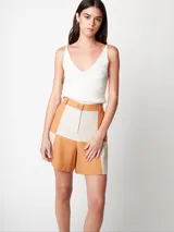 Short de lino color beige y naranja, de tiro alto con elástico en la pretina trasera, cierre delantero y botón, bolsillos delanteros y dobladillo invisible.