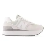 Championes New Balance 574 de dama, color blanco con detalles en gris. Presentan capellada de gamuza y mesh, entresuela con tecnología ENCAP y suela de goma.