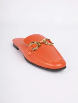 Zuecos abiertos de símil cuero color negro, con punta cuadrada, aplique metálico dorado en la parte superior y taco bajo.