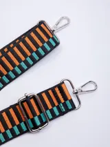 Correa de tela para cartera con diseño geométrico a rayas horizontales en colores negro, naranja y turquesa. Incluye mosquetones metálicos plateados en los extremos y hebilla metálica para regular el largo.