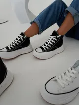 Championes tipo botita de caña alta con diseño bicolor, cuerpo en color negro y suela de plataforma gruesa en color blanco con base de goma.