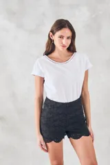 Remera blanca de algodón peinado, manga corta con puños doblados y escote redondo con terminación de vainilla calada.