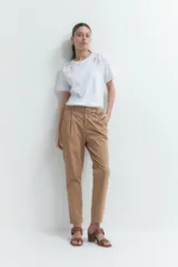 Pantalón de vestir color bordó, de corte recto, con bolsillos laterales y traseros. Se ajusta a la cintura con cinturón de cuero marrón.
