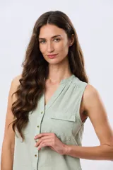 Musculosa de lino color beige, con cuello mao y escote en V, cierre frontal con botones y dos bolsillos plaqué con solapa en el pecho.