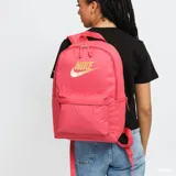 Mochila Nike Heritage color rosa con logo marrón. Tiene un compartimento principal con funda para laptop de hasta 15 pulgadas y dos bolsillos frontales con cierre.