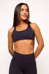 Top deportivo de espalda nadadora con diseño ergonómico, color marrón. Cuenta con un bolsillo integrado en la parte superior de la espalda y una abertura inferior, confeccionado en tejido técnico de alta compresión con detalles reflectivos.