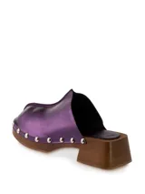 Zueco de cuero color marrón con plataforma de madera y tachuelas plateadas.