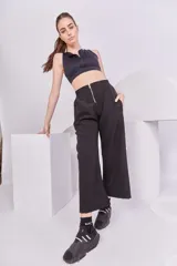 Pantalón negro de corte recto y tiro alto, con cintura elástica, bolsillos laterales y cierre metálico frontal.