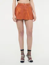 Minifalda de jean color naranja con efecto metalizado y ruedo desflecado.