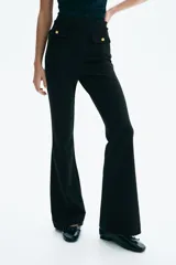 Pantalón acampanado de punto roma, color negro, con cintura elástica y solapas decorativas con botones dorados en la parte frontal.
