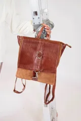 Mochila de cuero vacuno color negro, con tapa de cuero con textura croco color bordó y detalles en blanco. Tiene mosquetón de seguridad exterior, cierre interior, dos bolsillos interiores (uno con cierre y otro para celular), sujetador de llaves, forro completo y tiras ajustables. Se puede usar como mochila o como cartera.