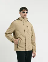 Campera 2 en 1 color beige, con cuerpo y capucha desmontable, manga larga, cierre frontal con botones a presión y bolsillos laterales engomados.