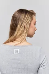 Remera de manga larga en tejido acanalado color gris, con escote en V y detalle de puntilla en el borde del cuello.