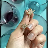 Aros con forma de estrella, bañados en oro de 18k y cristales micropavé. Cierre con pasante.