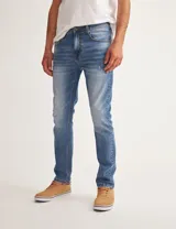 Pantalón de jean azul de corte slim fit, con lavado medio y detalles de desgaste.