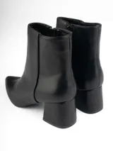 Botines negros de cuero sintético con punta fina, cierre lateral y taco cuadrado.