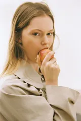 Chaqueta corta color beige, confeccionada en gabardina, con cuello solapa redondeado, mangas largas con frunces y detalle de frunces con lazada en el delantero, cerrando con botones.