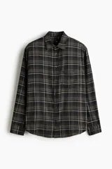 Camisa de manga larga con ajuste relajado, cuello inglés y un bolsillo de parche en el pecho. Presenta un estampado de cuadros en tonos de verde militar y negro, con finas líneas blancas.