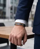 Pulsera masculina con correa de cuerina trenzada en color azul y placa central rectangular con baño de oro y detalles en acero.