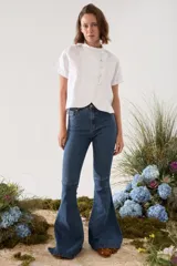 Blusa de lino verde de manga corta y corte recto, con cuello alto con volado y cierre frontal cruzado con botoncitos dorados.