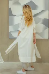 Vestido camisero blanco de lino, largo midi, con cuello camisero, mangas 3/4 y cierre frontal con botones.